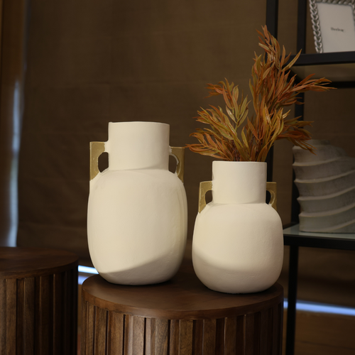 Two white aluminium vases on a wooden surface with a blurred background