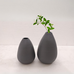 Two gray textured vases on a white surface with a light gray background