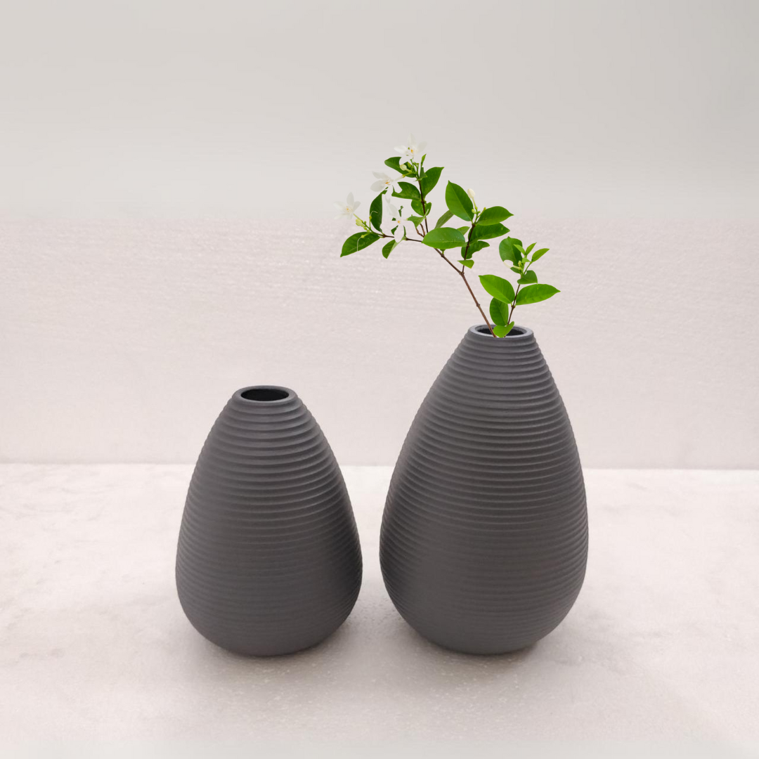 Two gray textured vases on a white surface with a light gray background