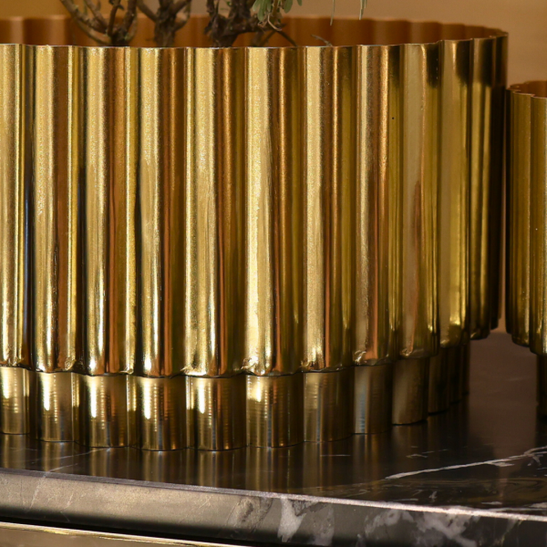 Gold metallic vase with ribbed texture on a dark surface