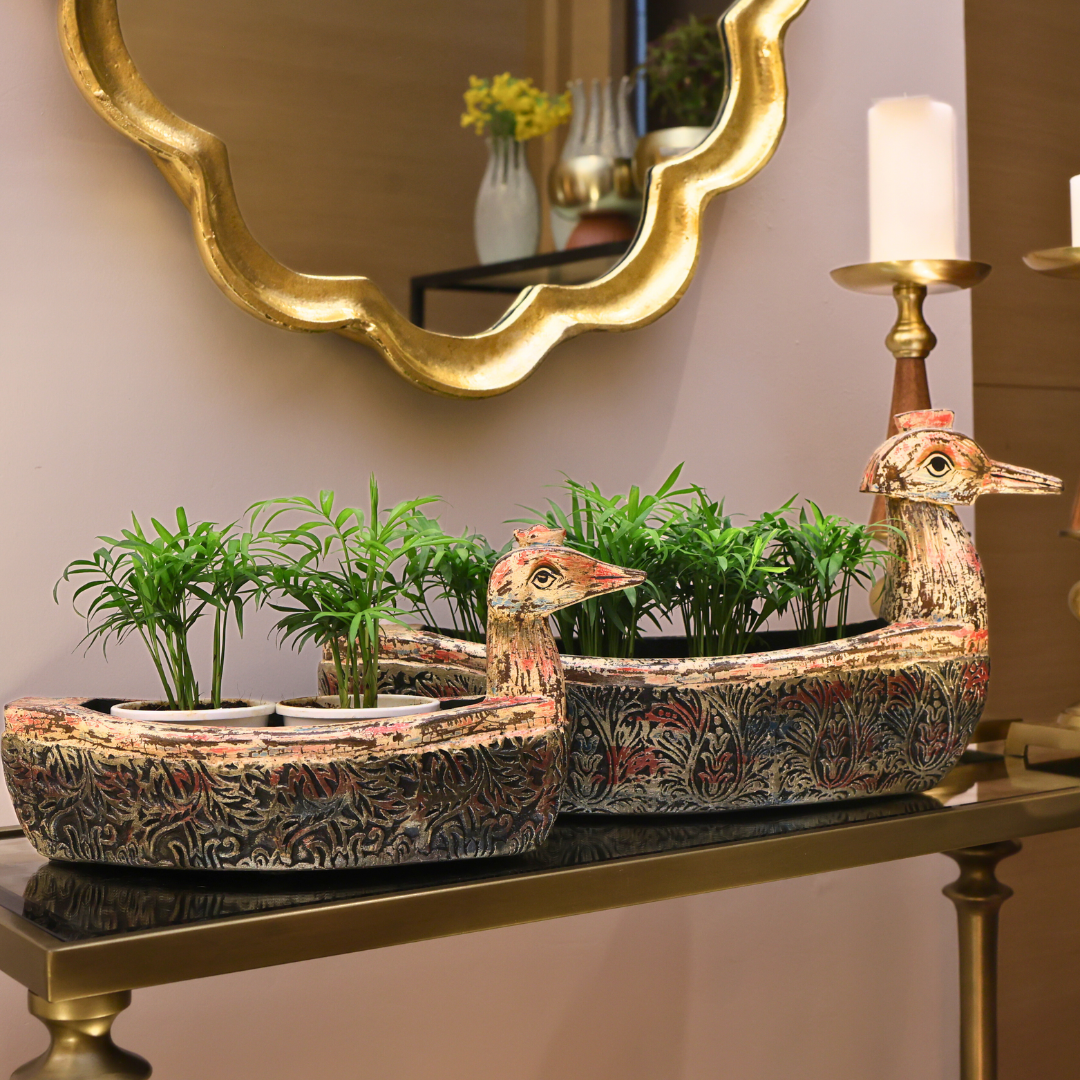 Decorative planter shaped like a boat with ducks on a table in front of a mirror.